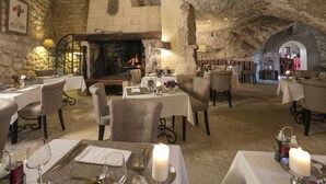 A restaurant with stone walls, a fireplace, and tables set for dining. - Le Mas d'Aigret (Les Baux-de-Provence)