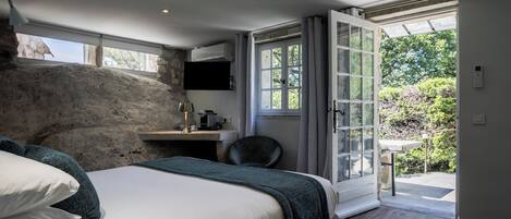 A bedroom with a large bed, a desk, a chair, and a view of the outdoors through a sliding glass door.