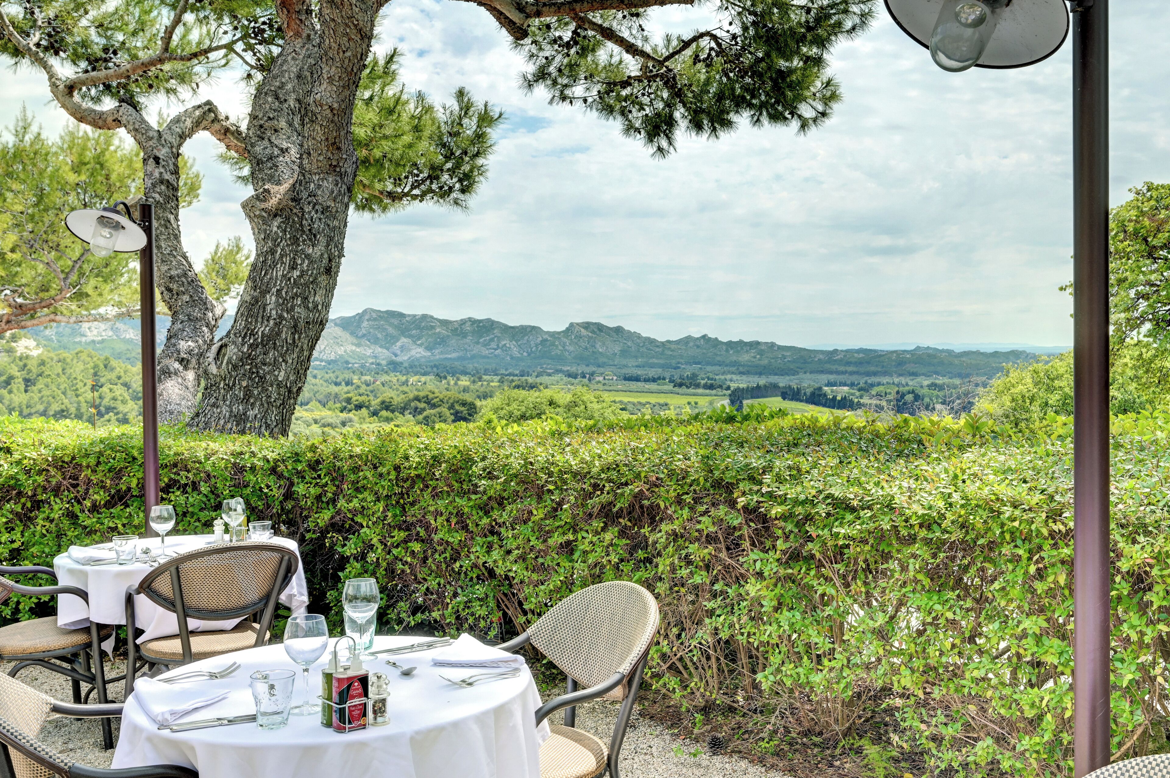 A table set outdoors with a view of a vineyard and mountains in the background.