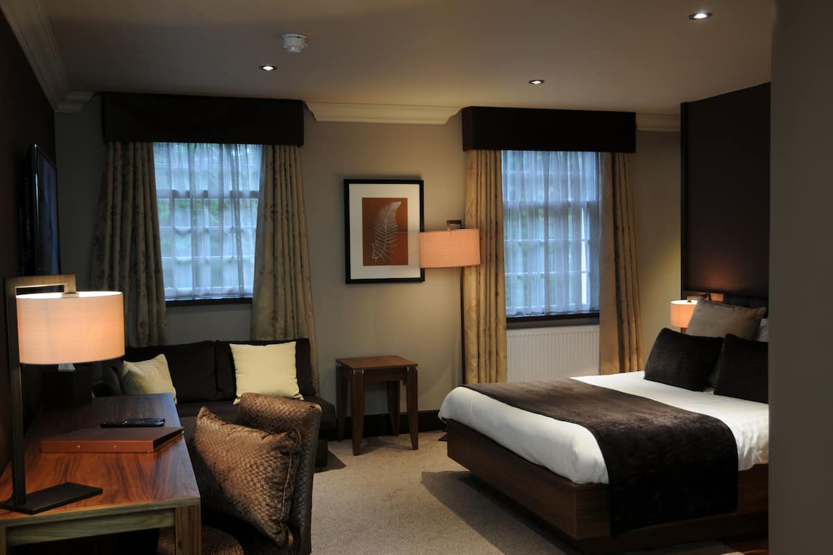 A hotel room with a bed, a desk, a chair, and a small table.