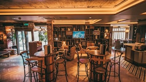 Un área de bar acogedora con mobiliario de madera, una pantalla de televisión y una pared de ladrillo.