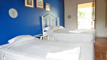 A bedroom with two beds, a white metal headboard, and a blue wall.