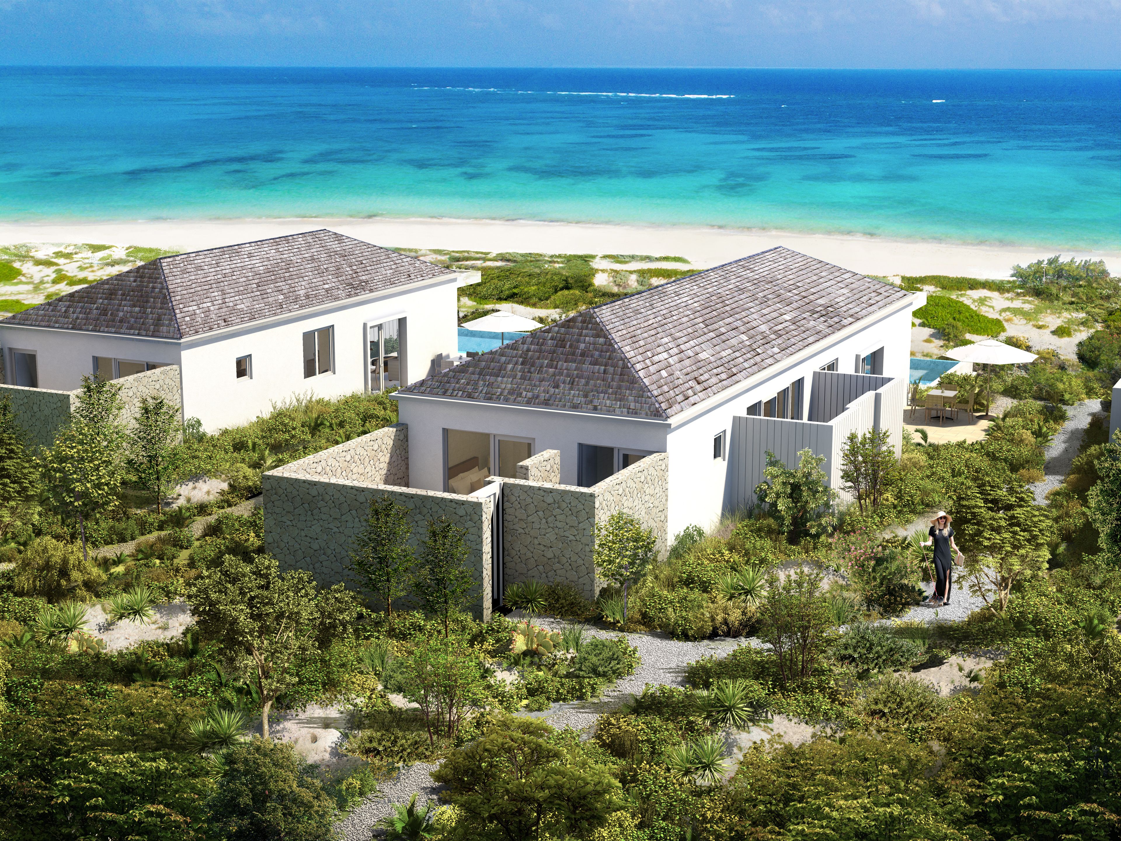 A modern beachfront property with two detached houses, a pool, and a lush garden.