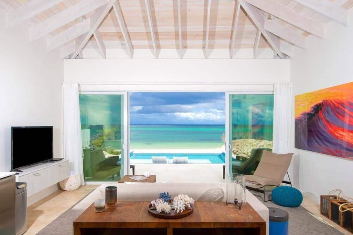 A modern room with a large glass door leading to a balcony with a view of the ocean.