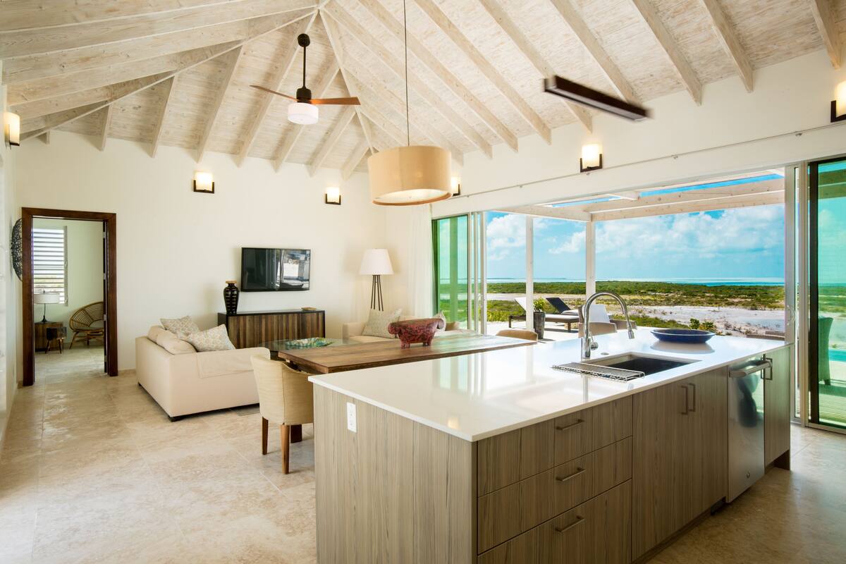 A spacious kitchen with a large island, wooden cabinetry, and a view of the beach.