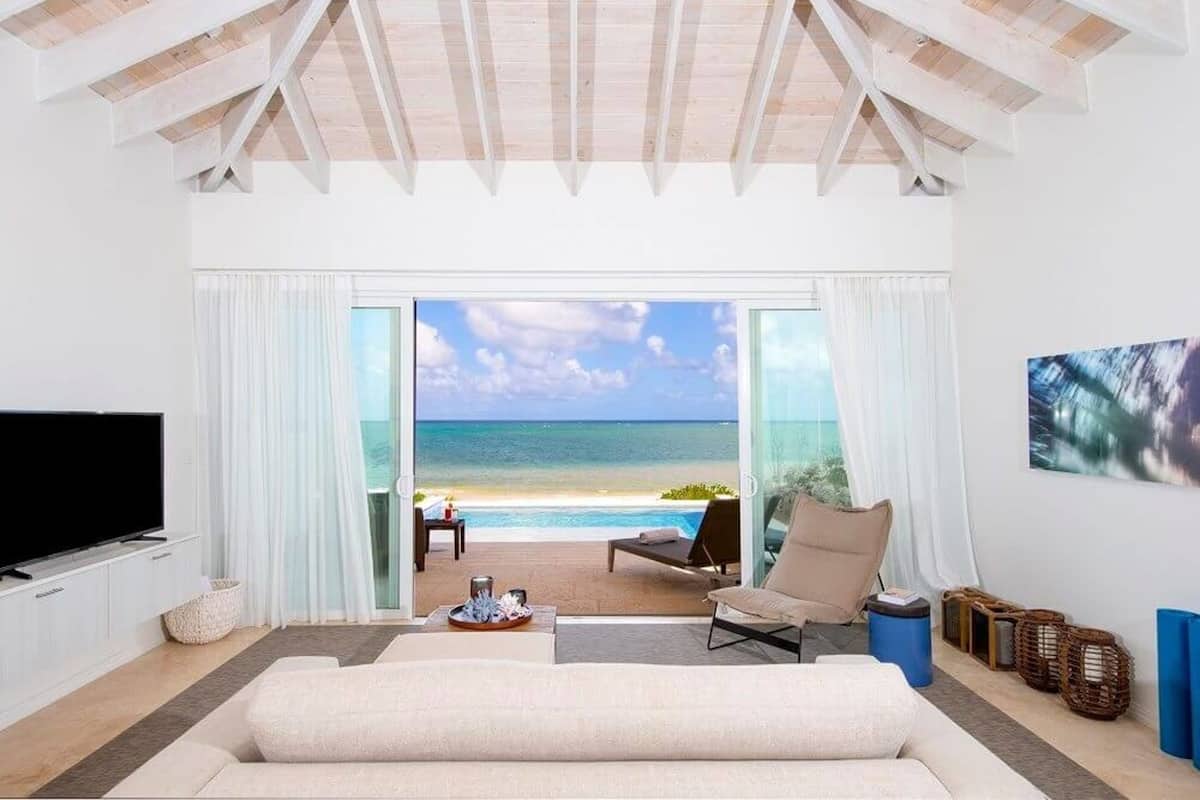 A spacious living room with a large window offering a view of the beach and ocean.