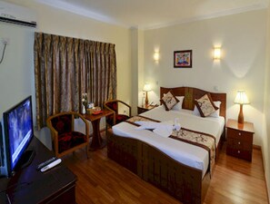 A hotel room with a bed, bedside tables, a desk with a chair, a television, and a window with curtains. - Millennium Hotel (Yangon)