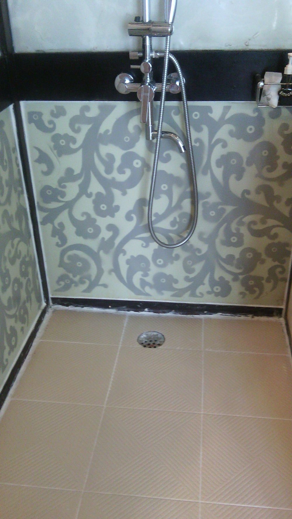 A shower area with patterned tiles and a drain.