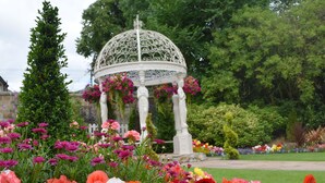 A garden with a white gazebo surrounded by colorful flowers. - The Lynnhurst Hotel (Johnstone)