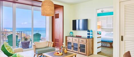 A spacious living room with a balcony, a wooden cabinet, a television, and a view of the city.