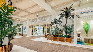 Un hall d’entrée spacieux, doté d’un plancher en bois, de grandes plantes en pot et d’un espace salon.