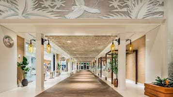 A hotel corridor with a wooden floor, modern lighting, and decorative ceiling artwork.