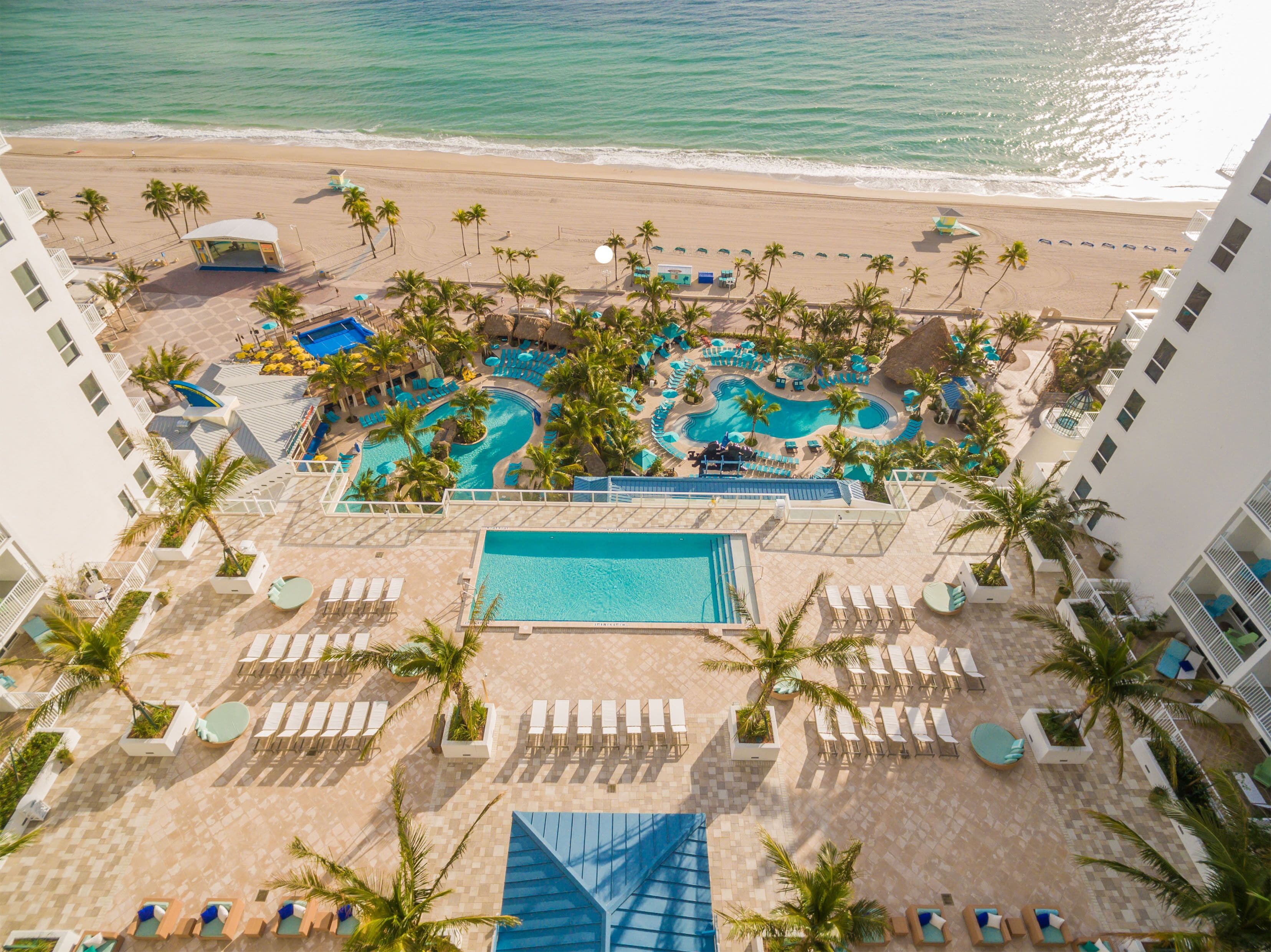 A resort with a large pool area, multiple swimming pools, and a beach view.