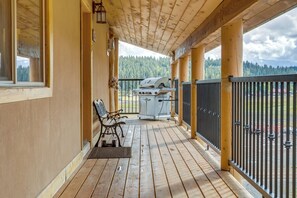 A wooden deck with a grill, a bench, and a view of a forest.