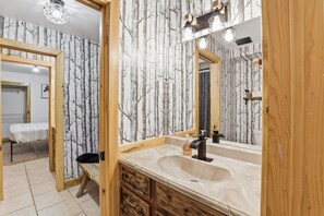 A bathroom with a large mirror, wooden vanity, and a sink.