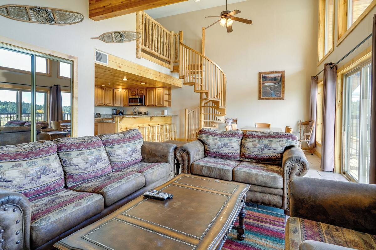 A spacious living area with a large sofa set, a coffee table, and a staircase leading to an upper level.