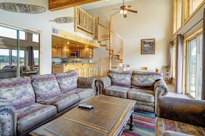 A spacious living area with a large sofa set, a coffee table, and a staircase leading to an upper level. - The Lodge at Duck Creek (Duck Creek Village)