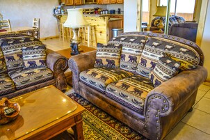 Una sala de estar con un sofá, cojines estampados, una mesa de centro de madera y una alfombra.
