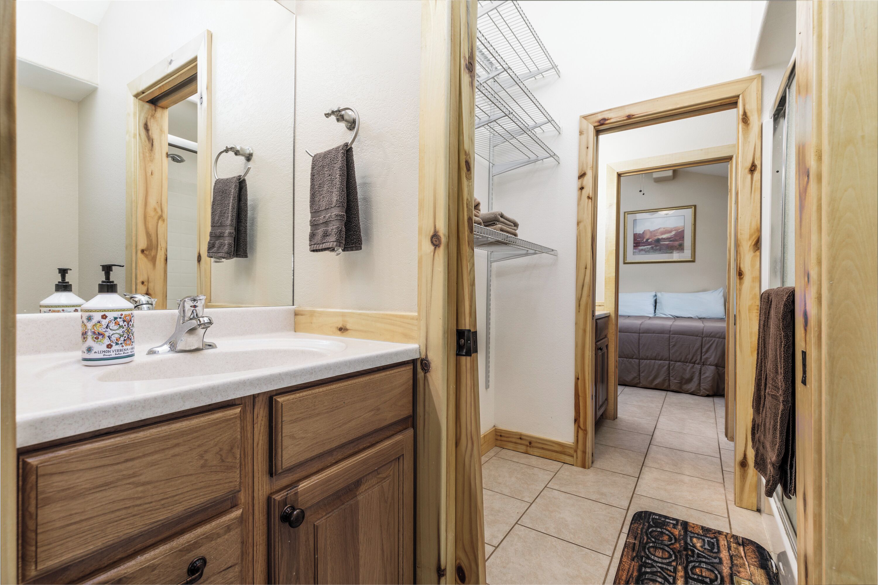 A bathroom with a wooden vanity, a large mirror, a sink, and a towel rack.