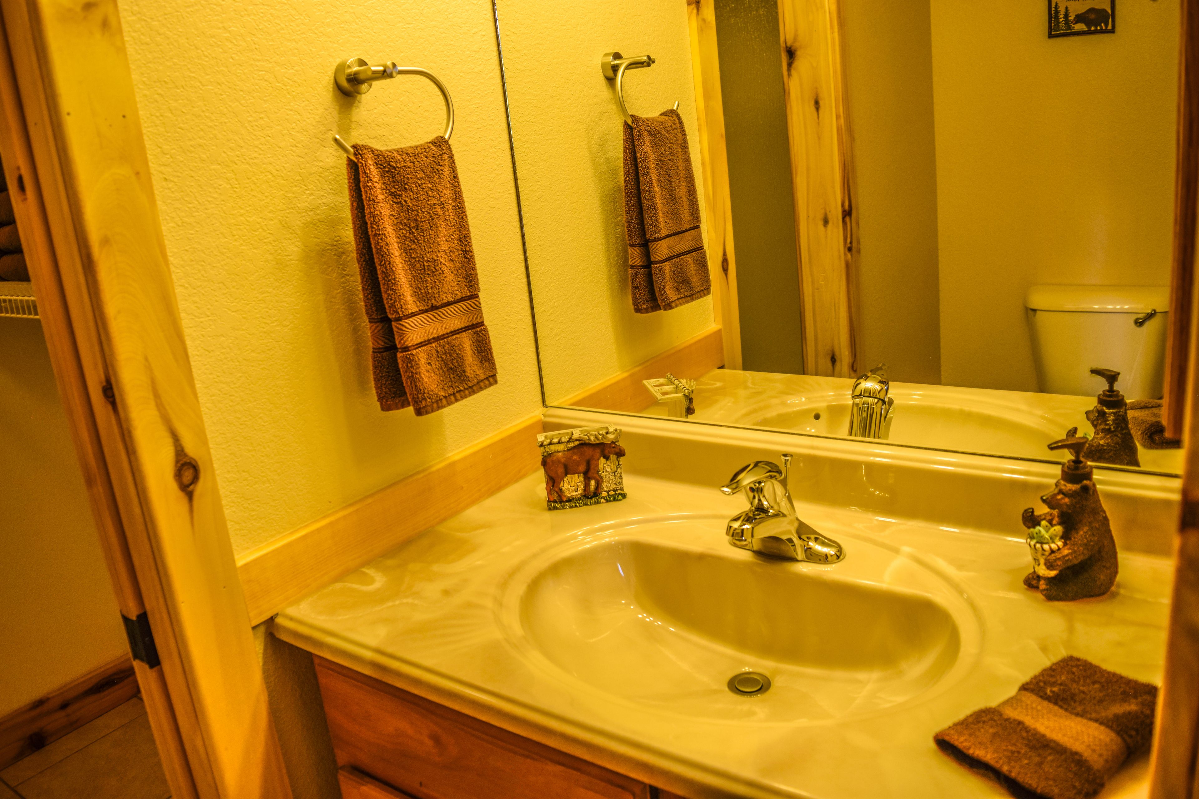 Une salle de bain avec un lavabo, un miroir et des toilettes. Des serviettes sont accrochées au mur.