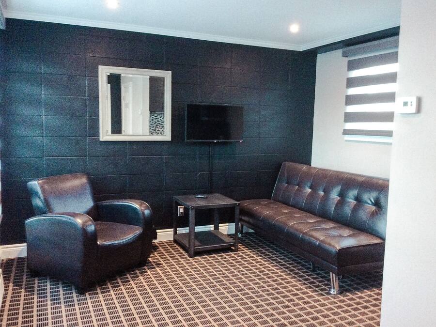 A living room with a dark wall, a brown leather sofa, a blue armchair, and a small table.