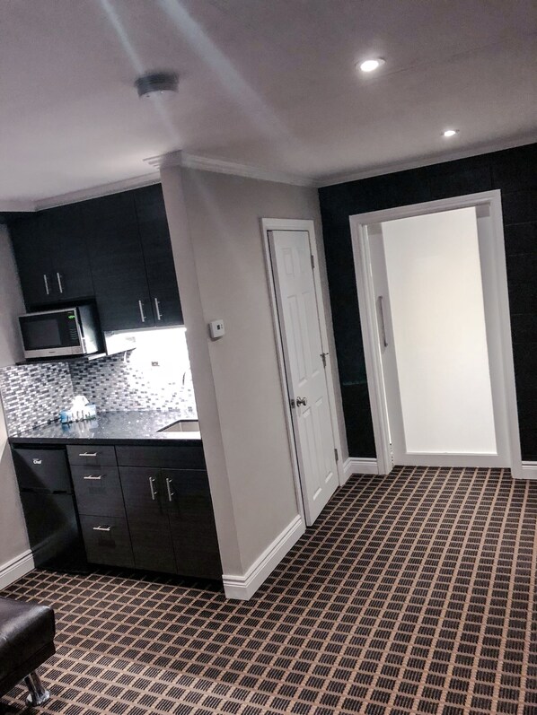 A compact kitchen with dark cabinets, a microwave, and a patterned floor.