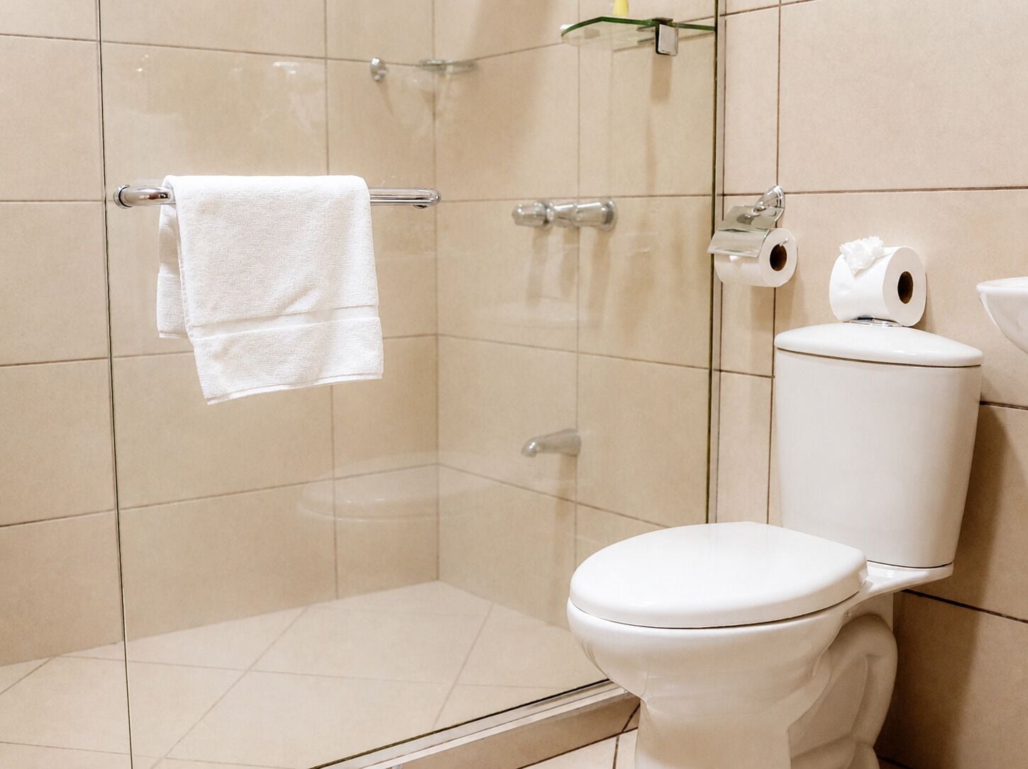 A modern bathroom with a toilet, a glass shower enclosure, and a towel rack.