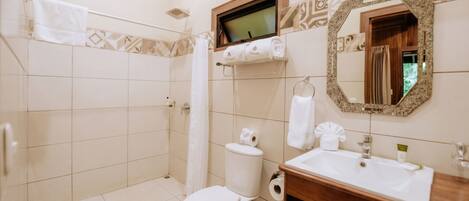 Une salle de bain équipée d’une douche, de toilettes, d’un lavabo et d’un miroir avec un cadre décoratif.