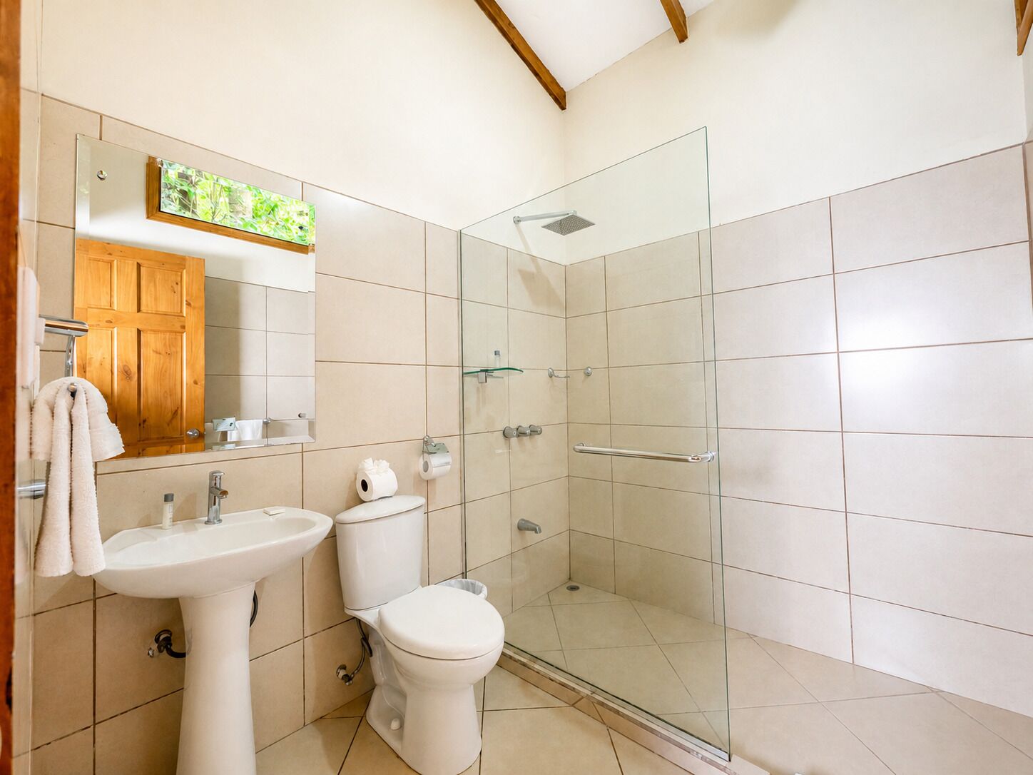 A bathroom with a glass-enclosed shower, a sink, a toilet, and a wooden cabinet.