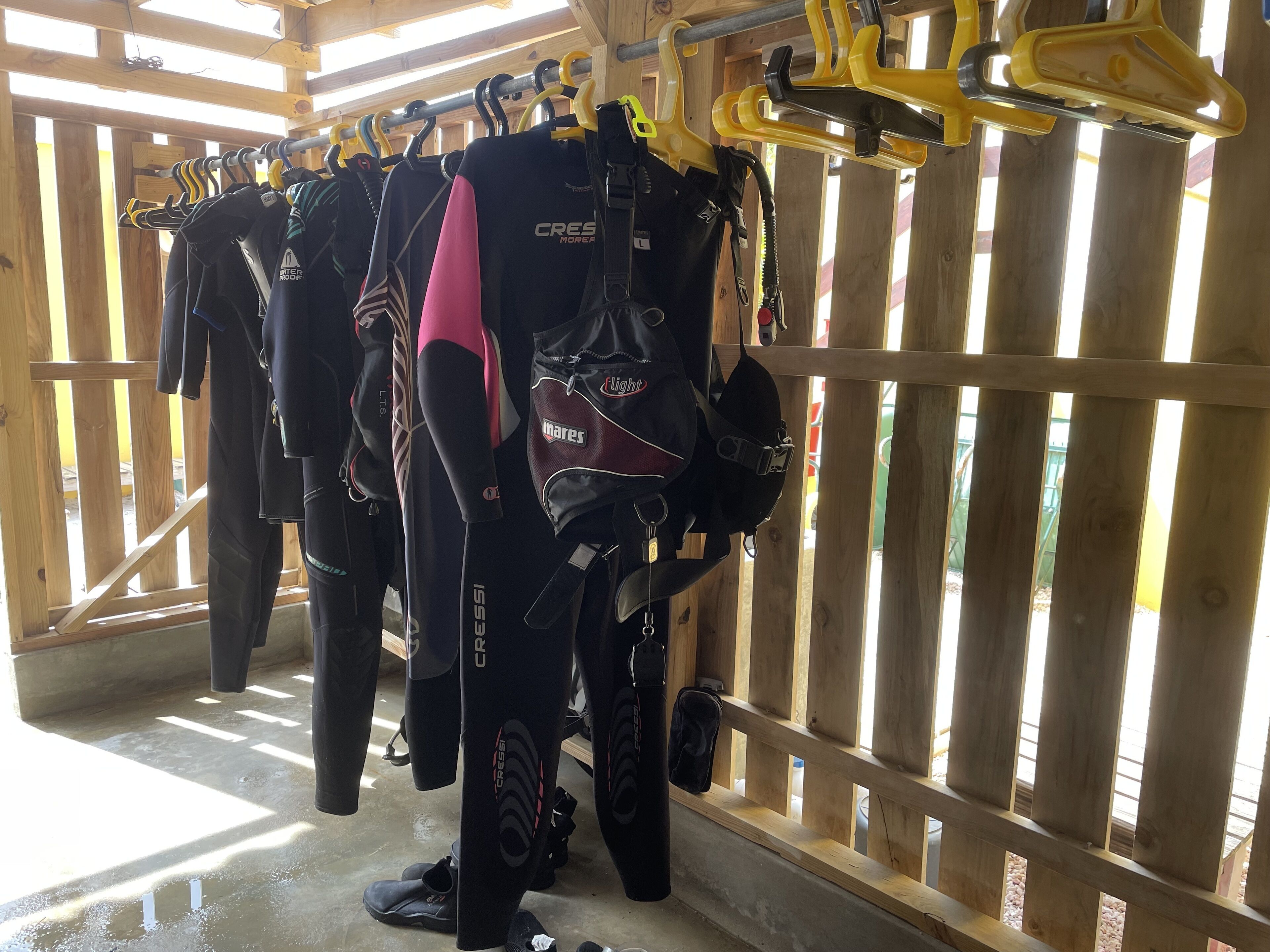 A wooden interior with a rack of wetsuits and diving gear.