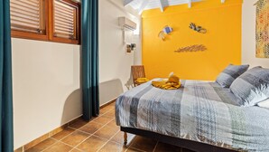 Een slaapkamer met een bed, een raam met zonwering, een stoel en een aan de muur bevestigde airconditioner.