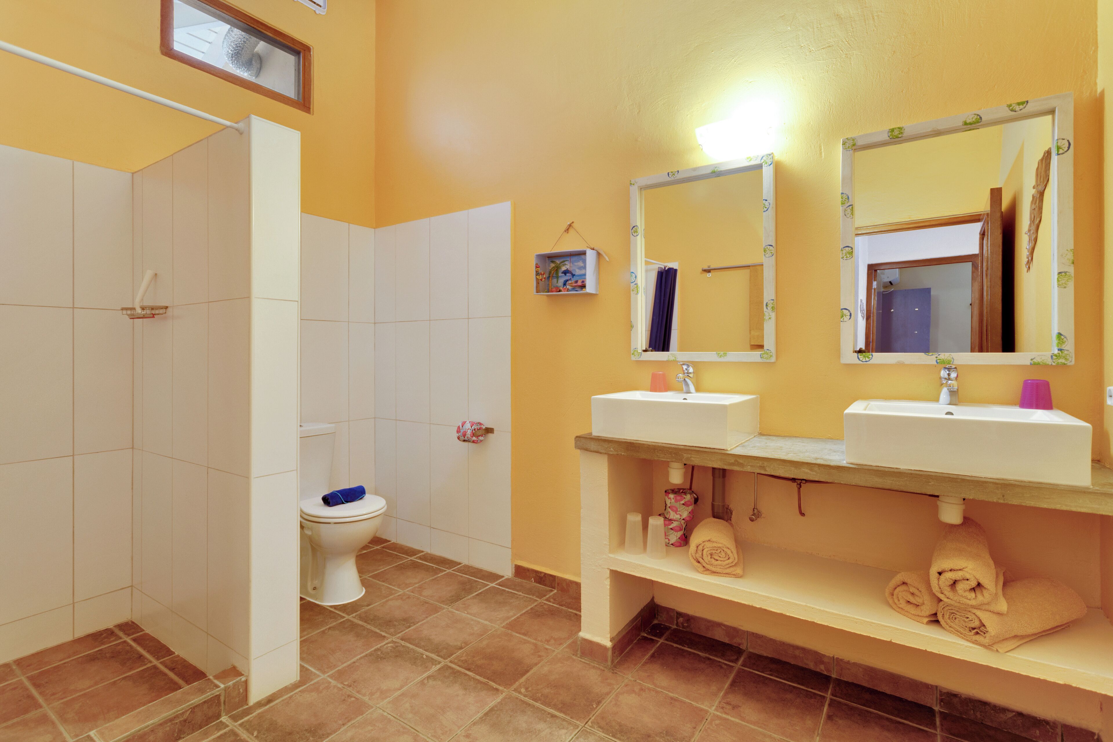 Un baño con inodoro, dos lavamanos, un espejo y ducha.