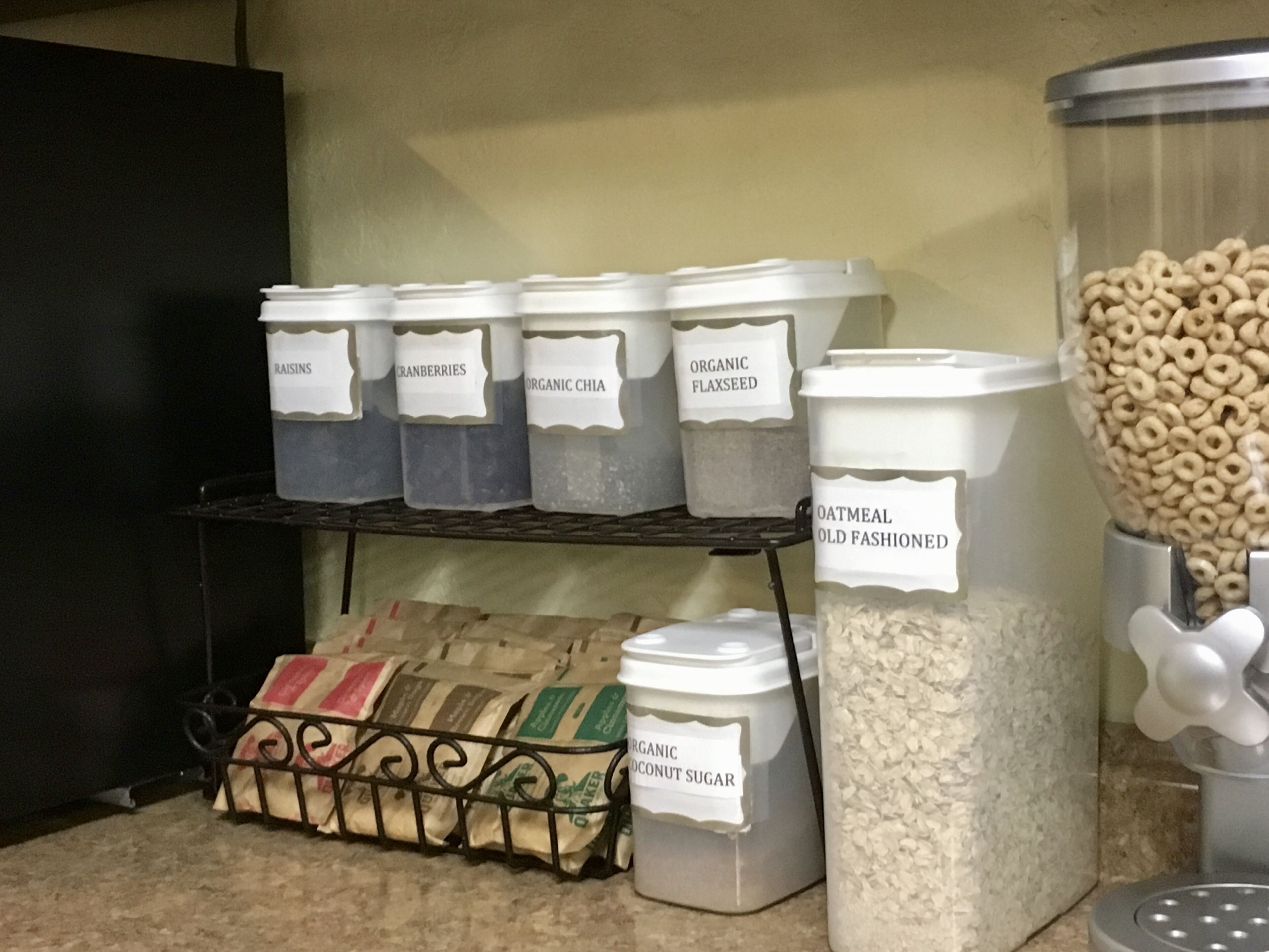 A kitchen pantry with labeled containers holding various food items like oats, organic flaxseed, and coconut sugar.