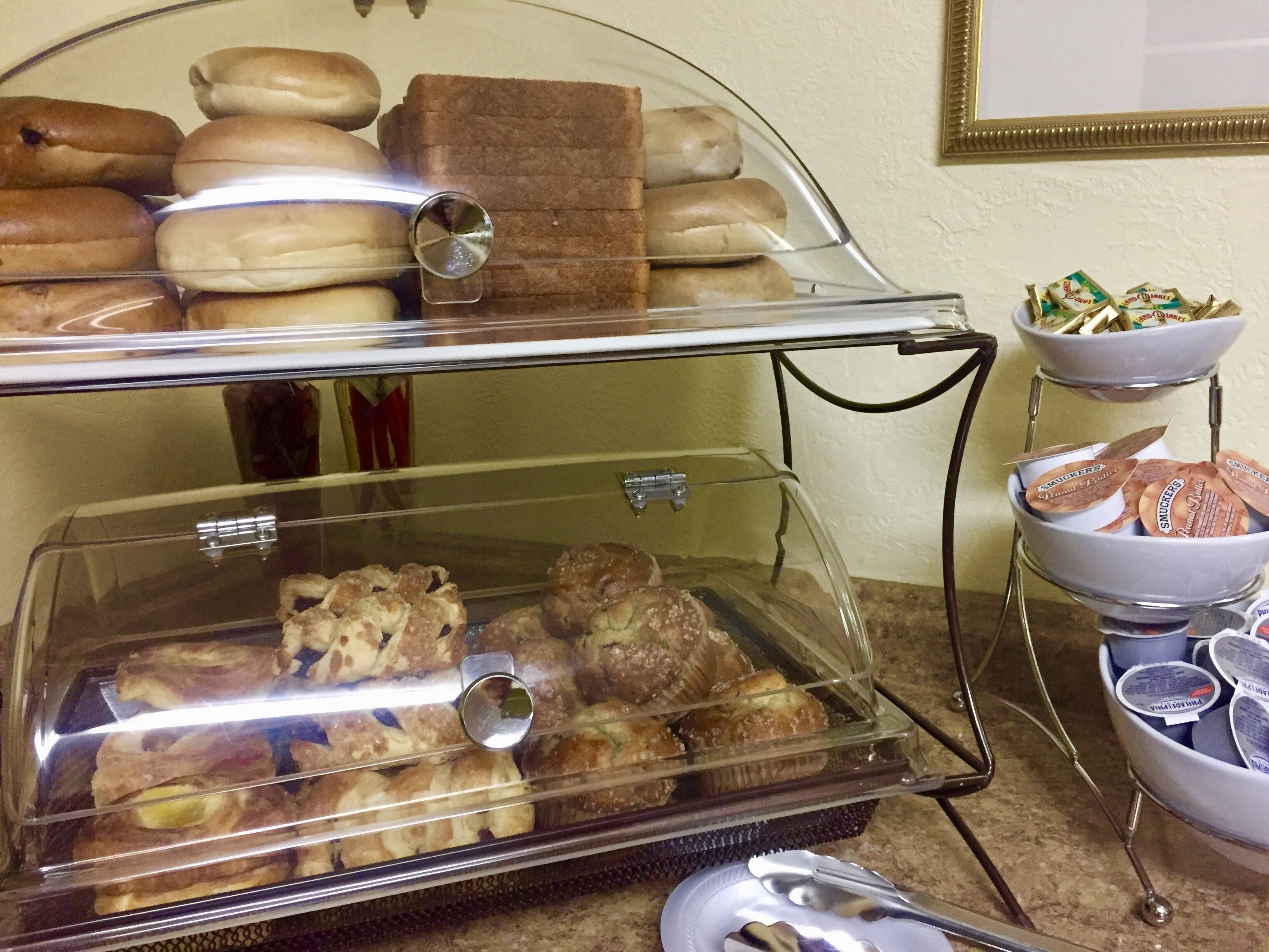 A buffet with various baked goods and snacks, including pastries and cookies, displayed in clear glass containers.