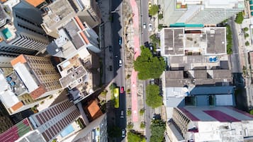 Une vue aérienne d’une ville avec de hauts immeubles, une allée centrale réservée aux piétons et un mélange de véhicules et de verdure.