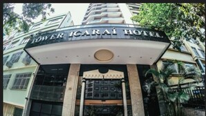 The exterior of the Tower Icarai Hotel with a prominent entrance, a sign above the door, and a small garden area with plants. - Tower Icaraí Hotel (Niteroi)