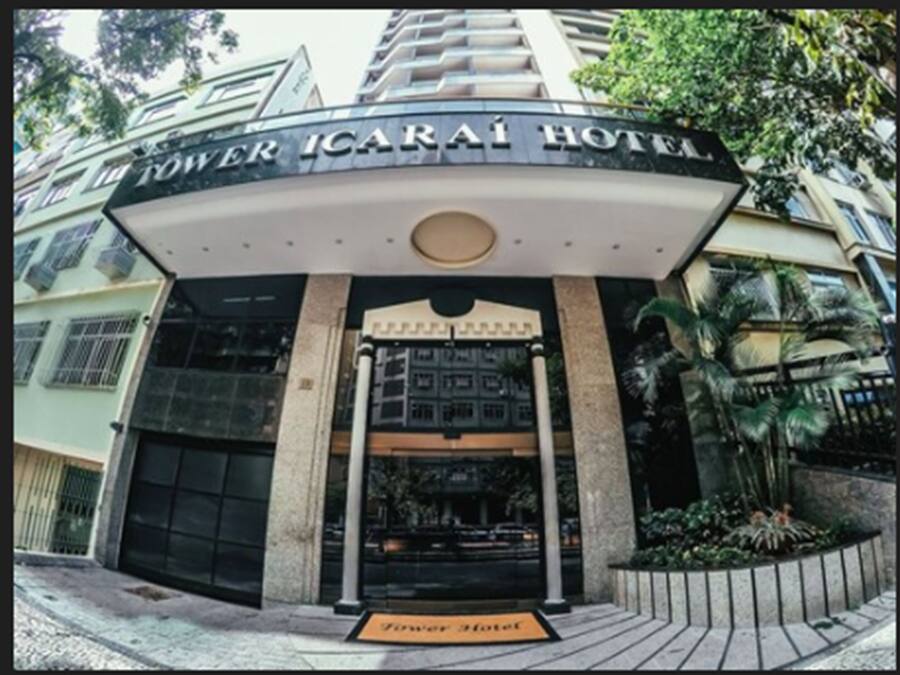 The exterior of the Tower Icarai Hotel with a prominent entrance, a sign above the door, and a small garden area with plants.