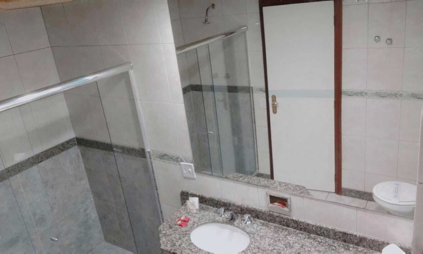 Un baño con cabina de ducha de vidrio, lavamanos e inodoro.