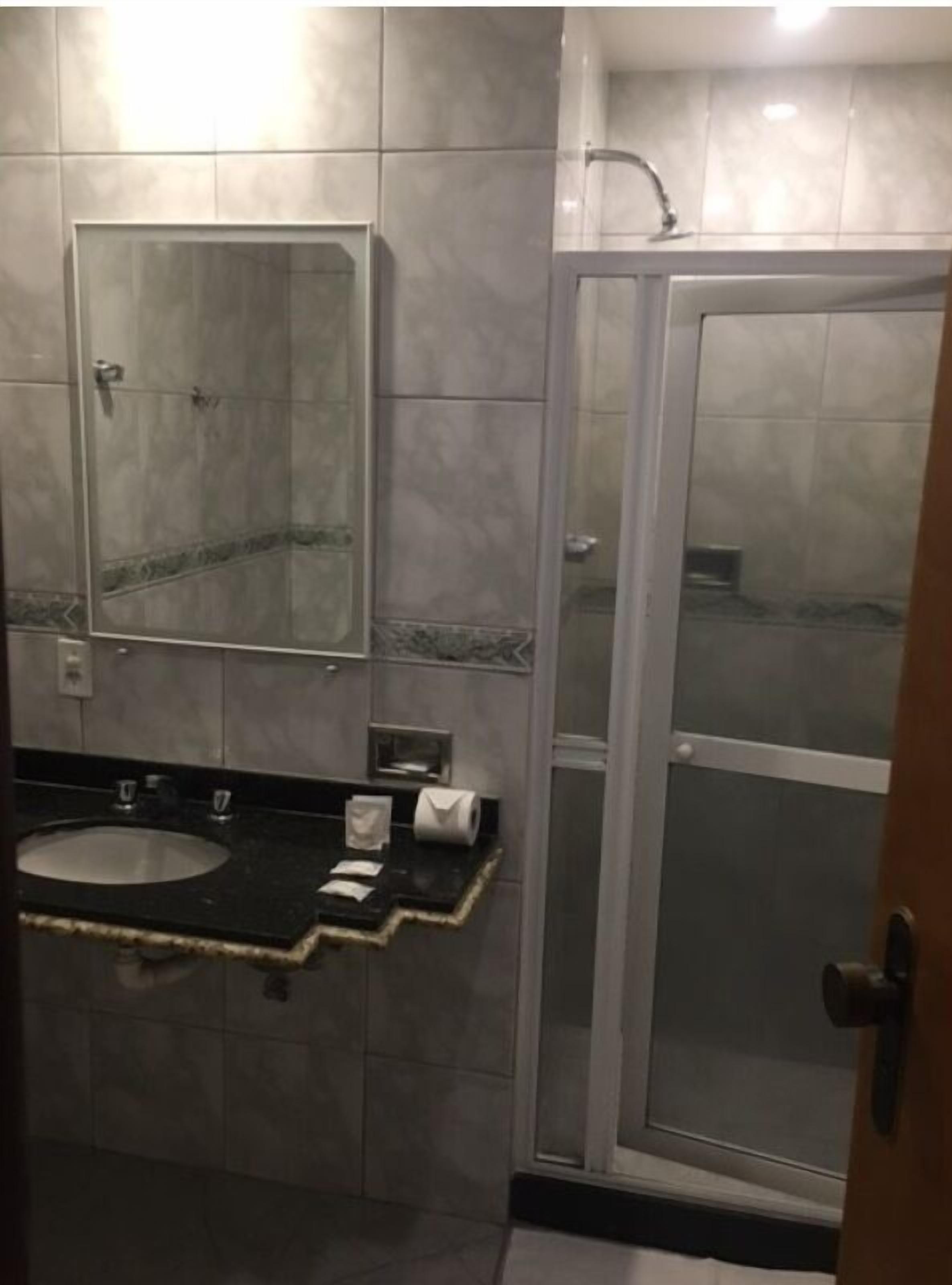 Een badkamer met een wastafel, spiegel en een douche met glazen wanden.