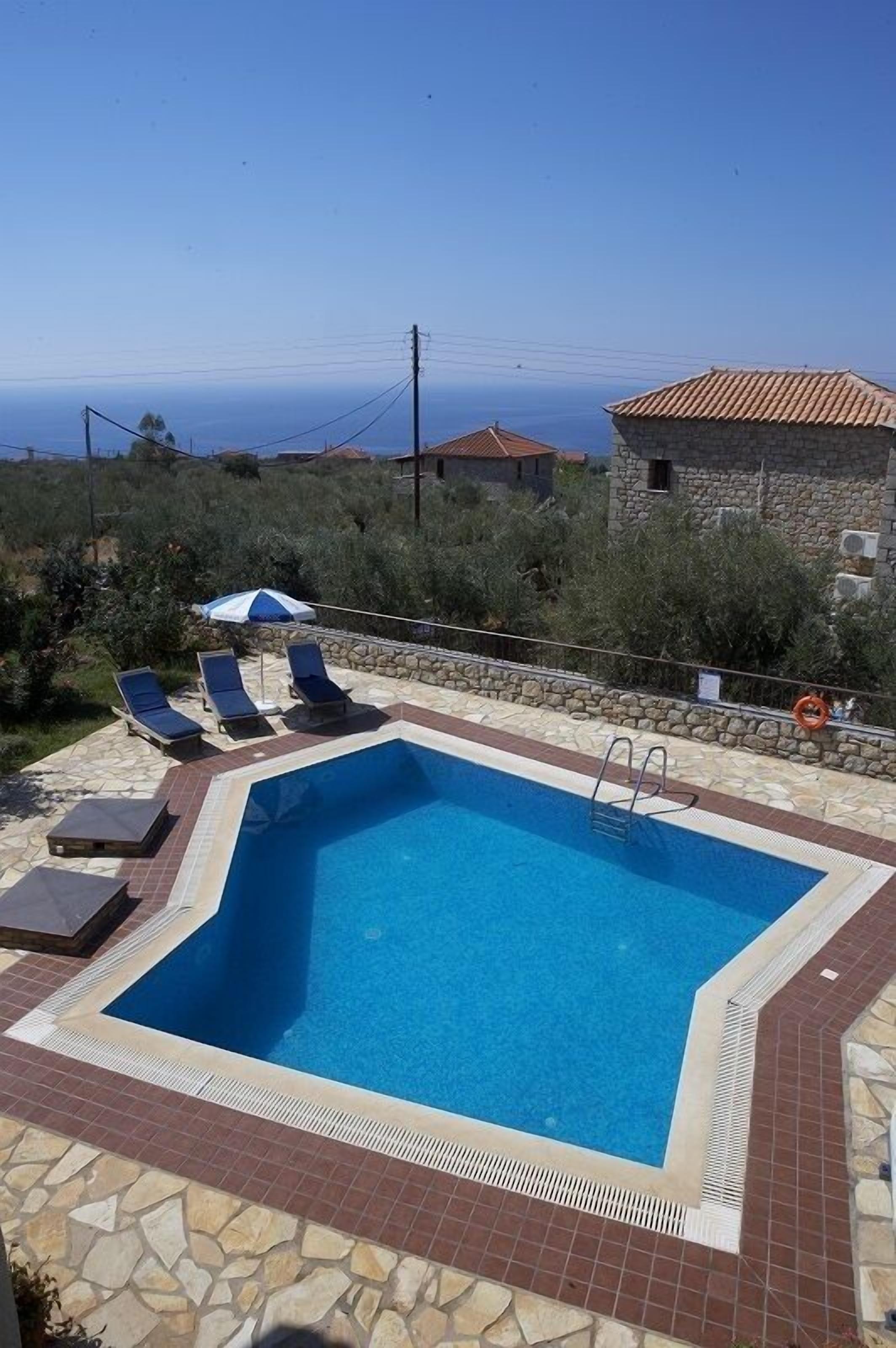A swimming pool with lounge chairs and a stone wall.