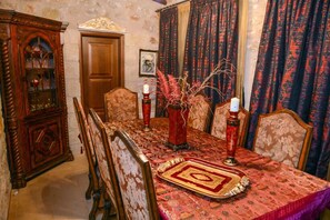 A dining room with a patterned tablecloth, wooden chairs, a decorative vase, and a candle holder. - Olympia Villas (West Mani)