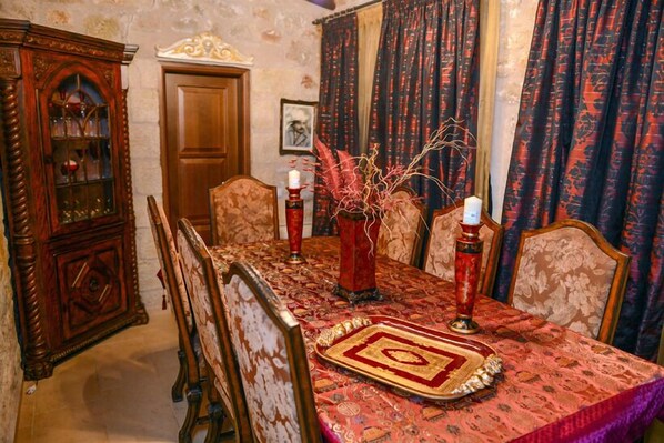 A dining room with a patterned tablecloth, wooden chairs, a decorative vase, and a candle holder. - Olympia Villas (West Mani)