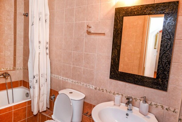 A bathroom with a bathtub, toilet, and sink. - Olympia Villas (West Mani)