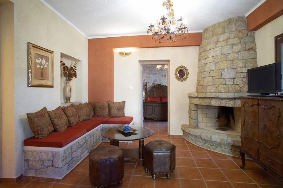 Una sala de estar con chimenea de piedra, un sofá, una mesa de centro y un televisor.