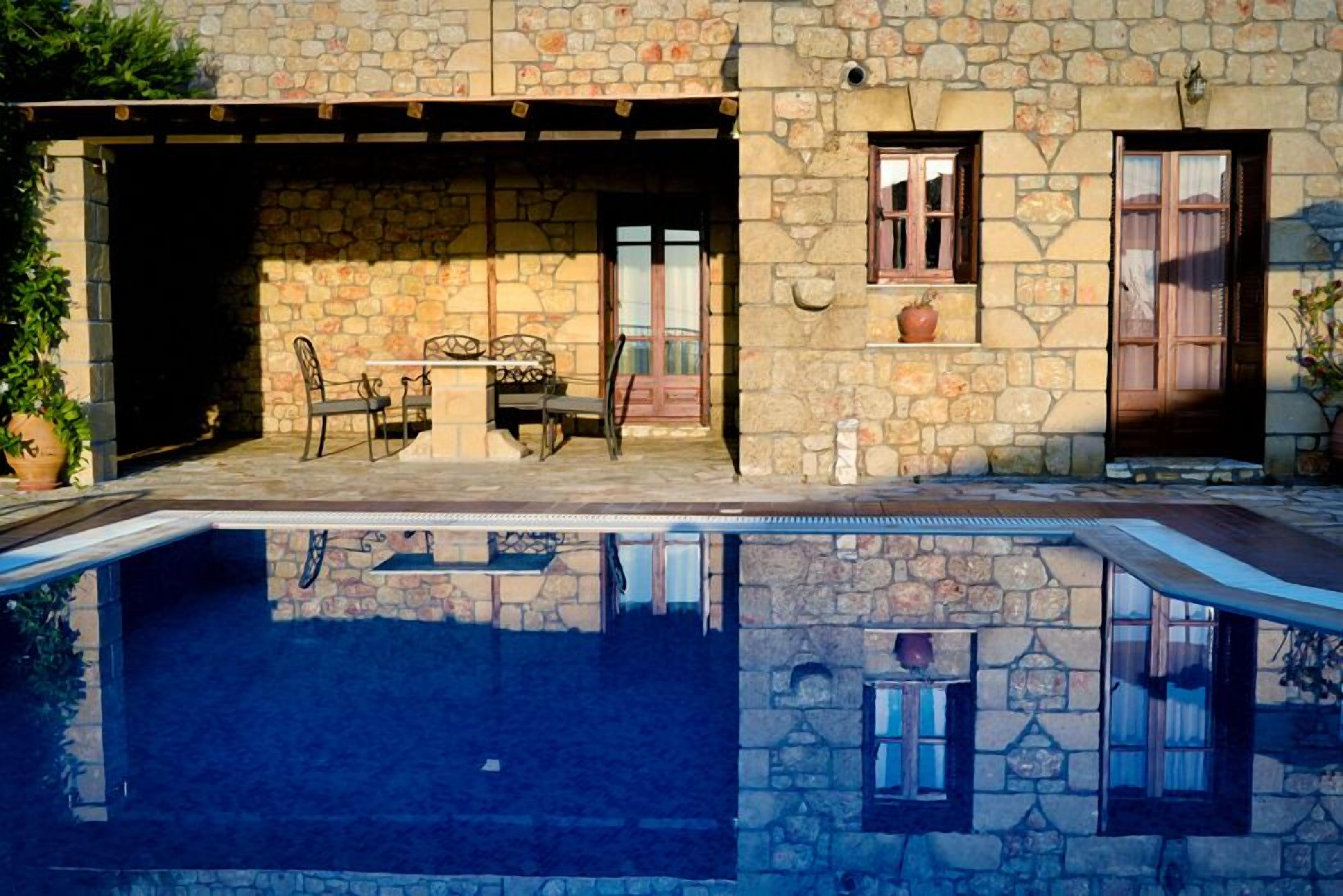 Un edificio de piedra con piscina, mobiliario exterior y fachada de piedra.