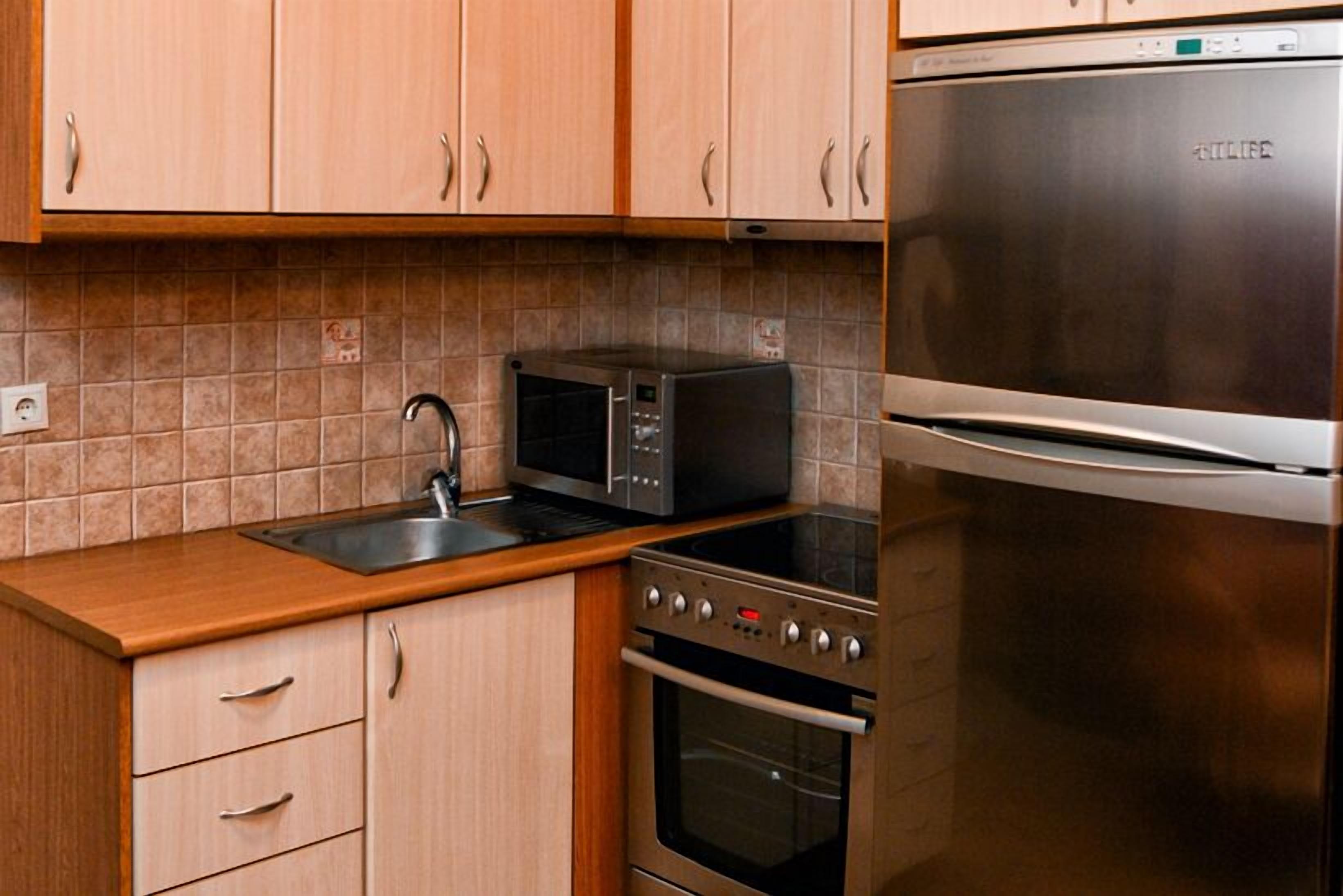 Una cocina con armarios de madera, un refrigerador de acero inoxidable, un microondas y un horno.