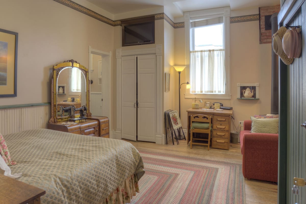 Une chambre à coucher comprenant un lit, une commode, un bureau, une chaise et une porte.
