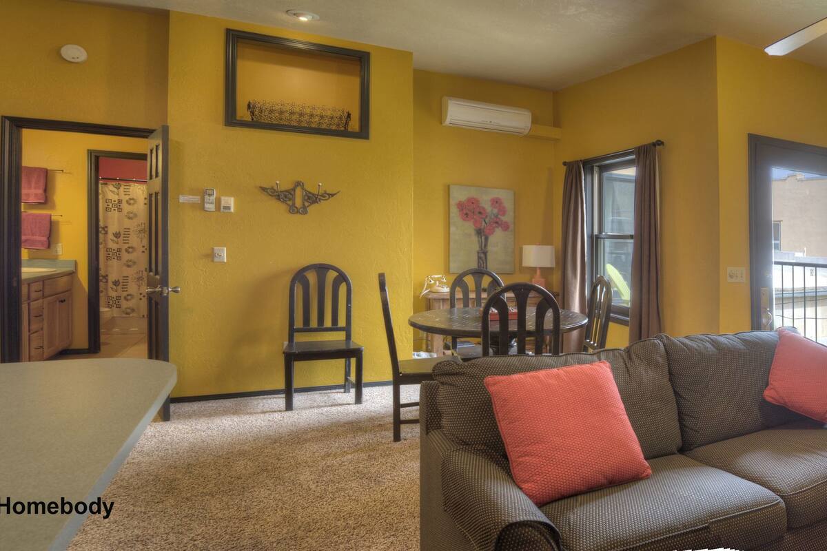 Un salon comprenant un canapé, des fauteuils, une table à manger et une grande fenêtre.