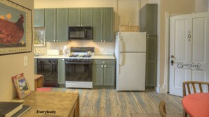 A compact kitchen with green cabinets, a white refrigerator, and a microwave. - Nobody's Inn (Durango)