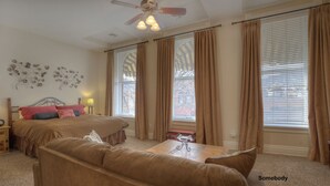 A bedroom with a bed, a sofa, a table, and a ceiling fan. - Nobody's Inn (Durango)
